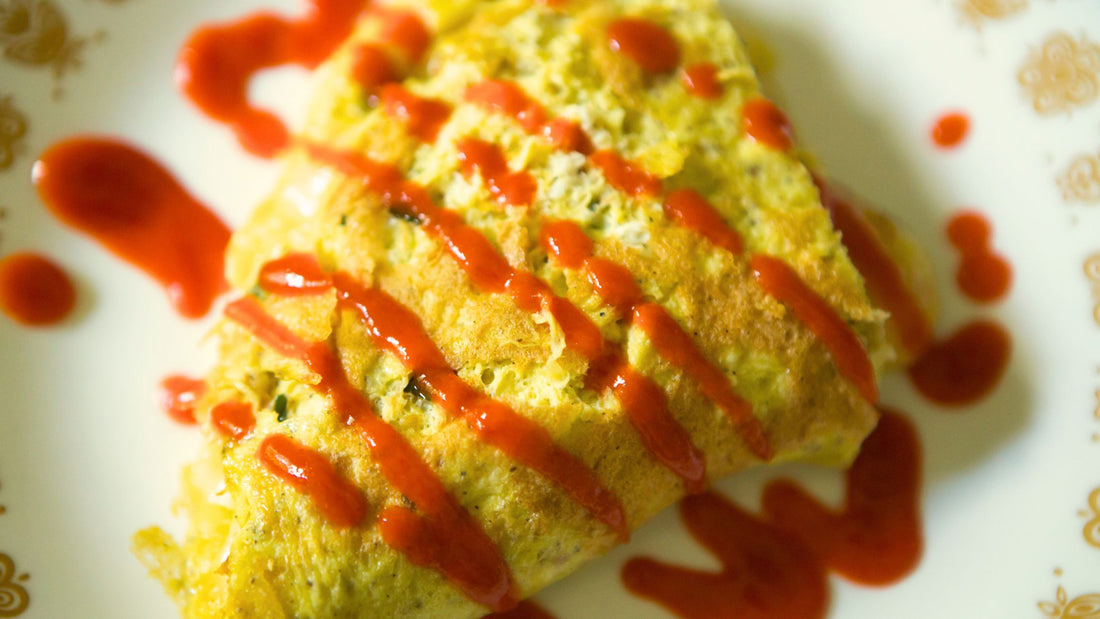 Features an omelet drizzled with hot sauce